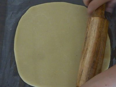 rolling badam burfi or badam katli dough using rolling pin