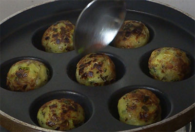 cooking balekai snacks or raw banana balls on all sides