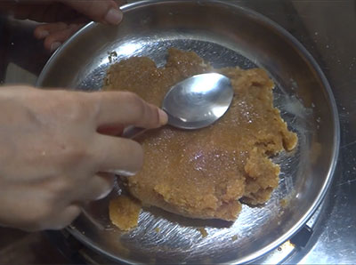 transfer bella kayi burfi or coconut jaggery burfi mixture to greased plate