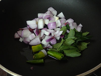 frying onion, chili and curry leaves for mixed flour poori or hittina vade